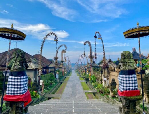 People walking through a well-kept traditional Balinese village setting.